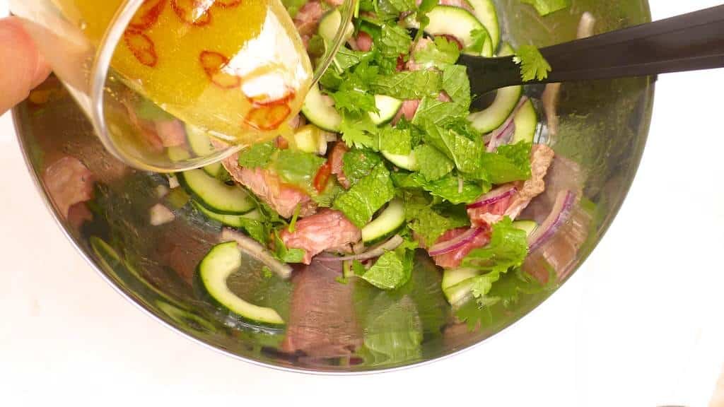 An easy Thai recipe: chilled Thai beef salad with cucumber, tomatoes, mint, cilantro and red onion in a spicy fish sauce and lemon marinade!